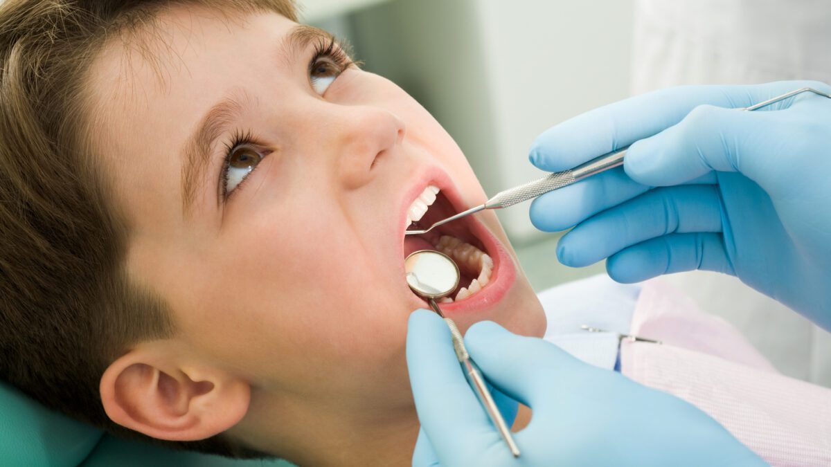 Child sitting in the dental chair being examined by the dentist