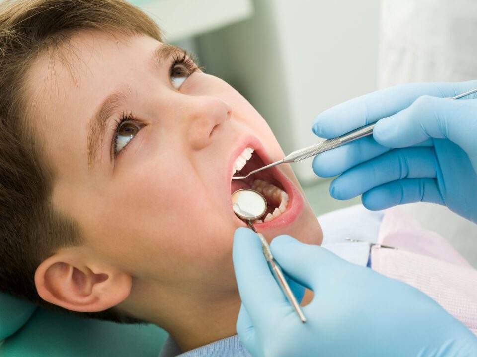 Child sitting in the dental chair being examined by the dentist